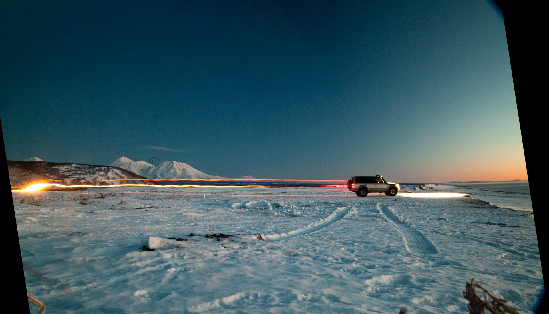 A truck driving through a snow covered field