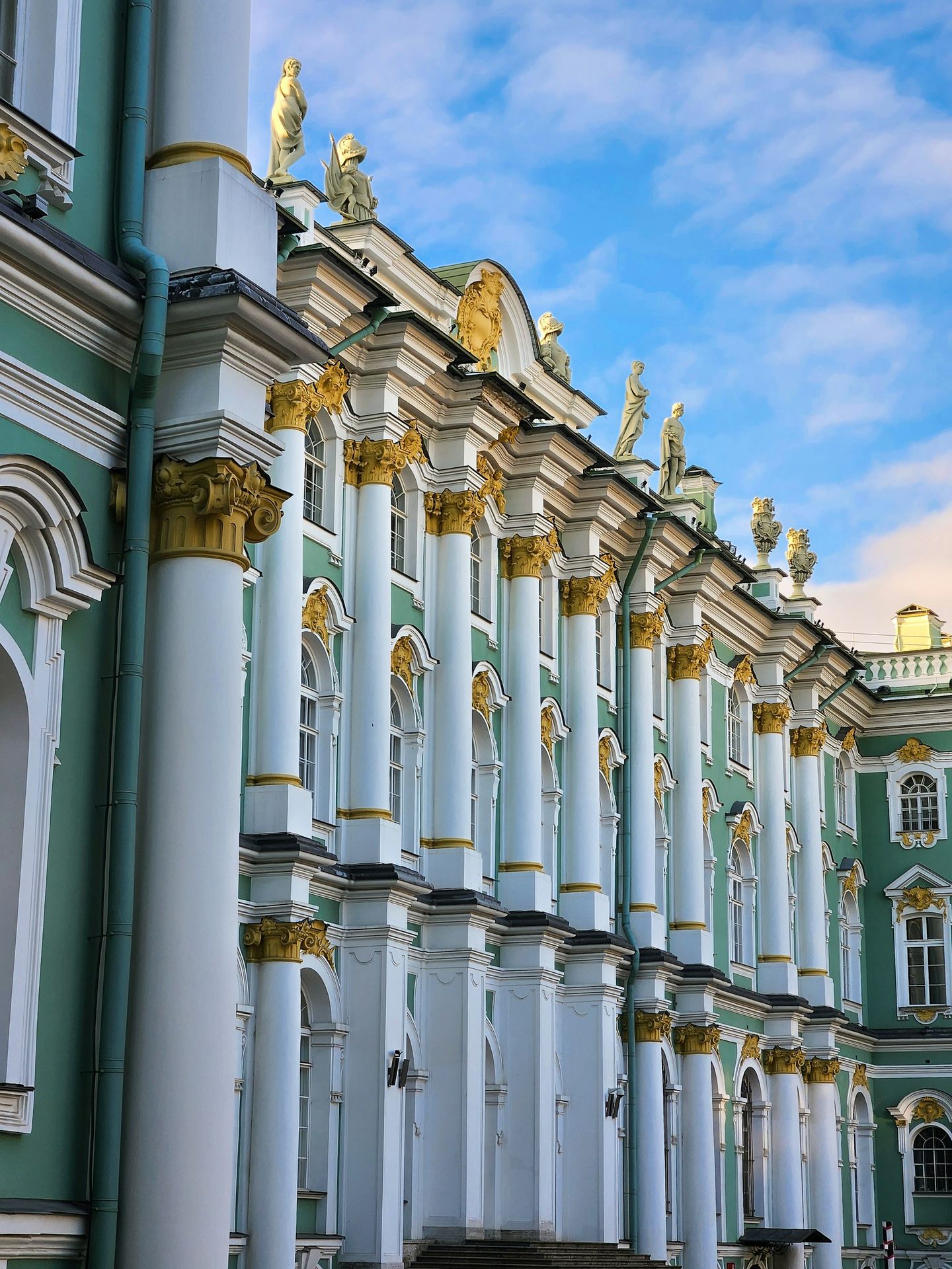 a row of white and green buildings with gold trim