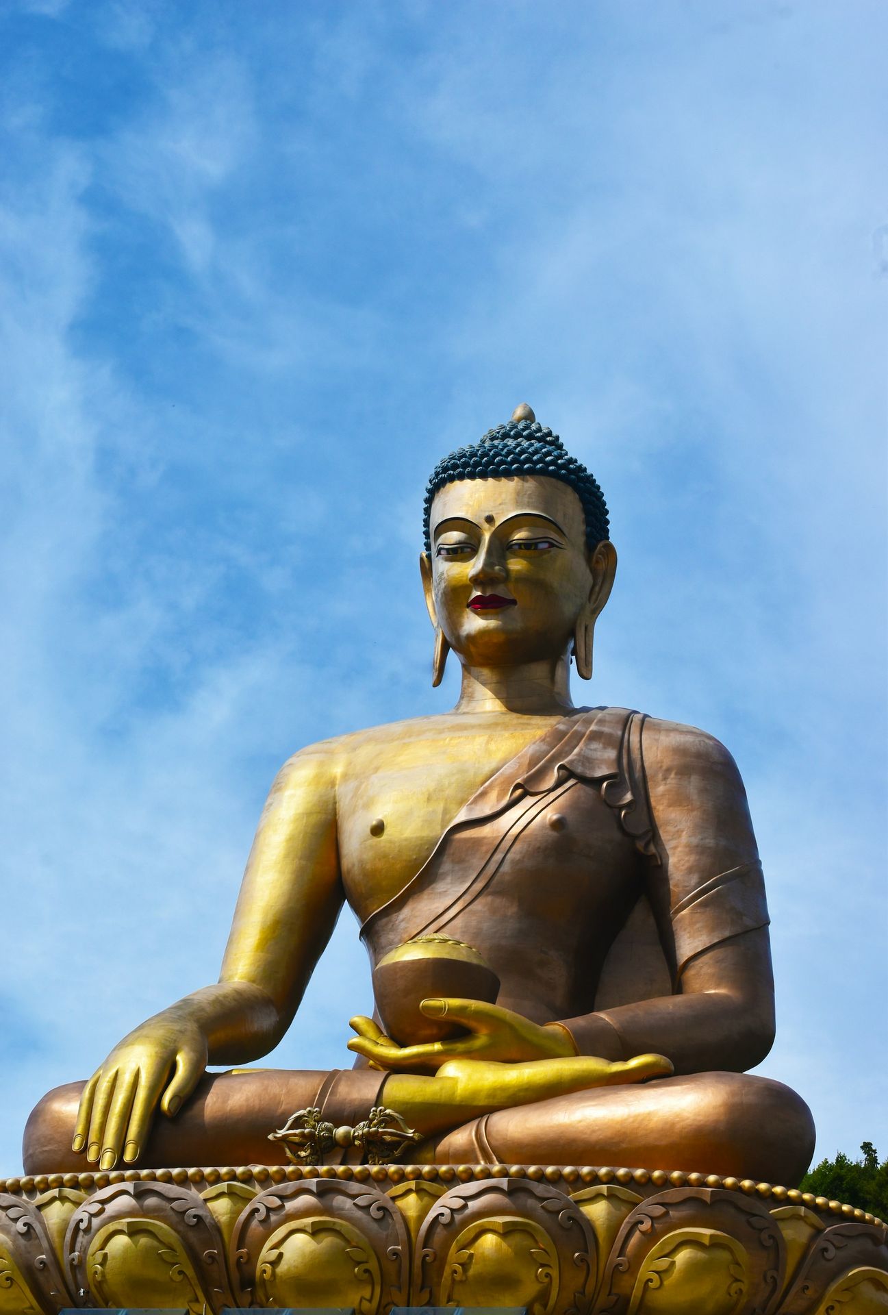 A large buddha statue sitting on top of a lush green field